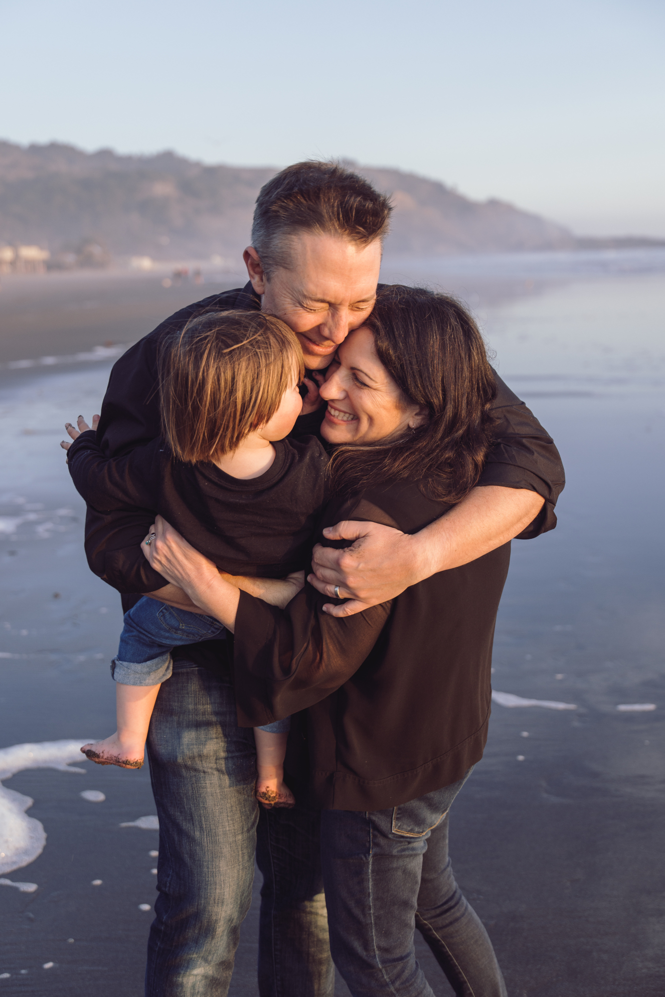 Family embracing in the surf during beach photo session